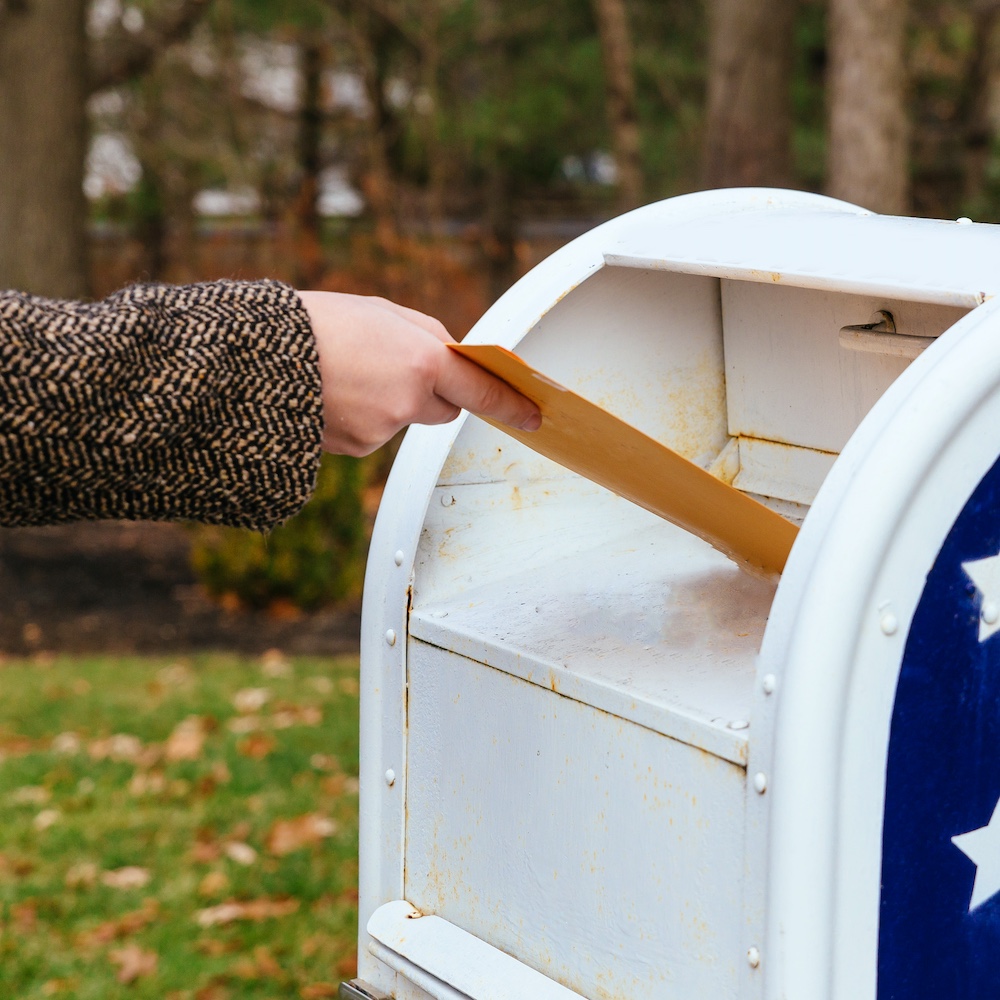 Person Putting Envelope into Mailbox